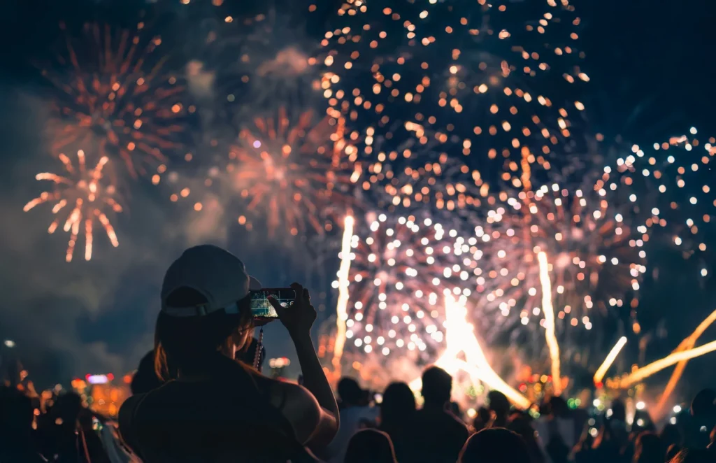 A woman recording a fireworks show on her phone.
