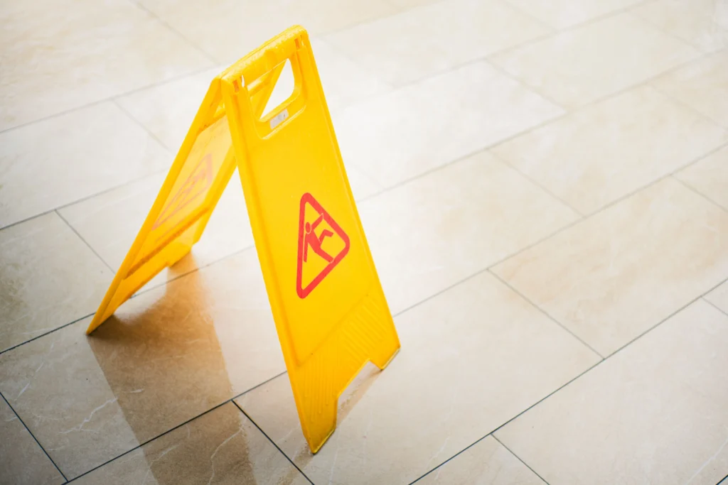 Yellow caution wet-floor sign standing on a tiled floor, indicating a floor that could cause a slip and fall accident.